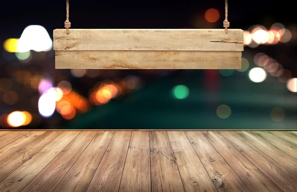 Wood table with hanging wooden sign on city lights night blurred background