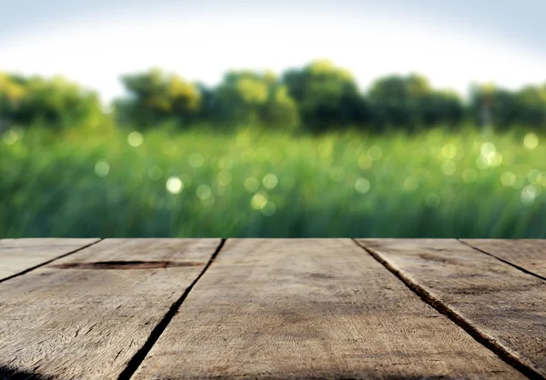 Mesa de madera y hierba verde fondo borroso — Foto de Stock