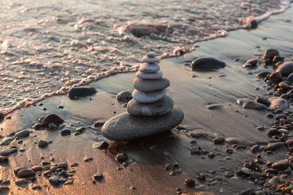 Sahile su sıçrayan çakıl taşı piramidi. Arka planda dalgalar.