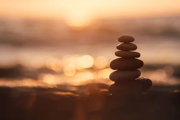 Gün batımında kumsalda taş piramit, güzel deniz manzarası, dinlenme ve deniz kenarında tatil konsepti., 