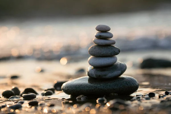 Gün batımında kumsalda taş piramit, güzel deniz manzarası, dinlenme ve deniz kenarında tatil konsepti., 