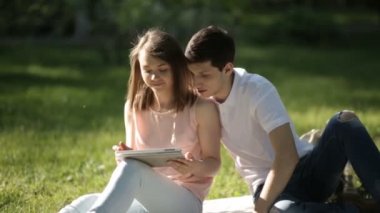 Kız parkta oturan ve tablet vasıl bakarak herifle