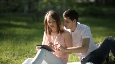 Kız parkta oturan ve tablet vasıl bakarak herifle