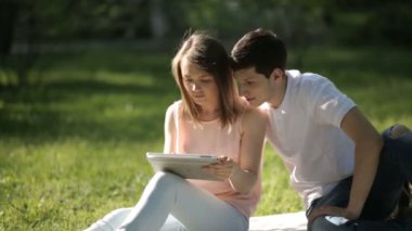 Kız parkta oturan ve tablet vasıl bakarak herifle