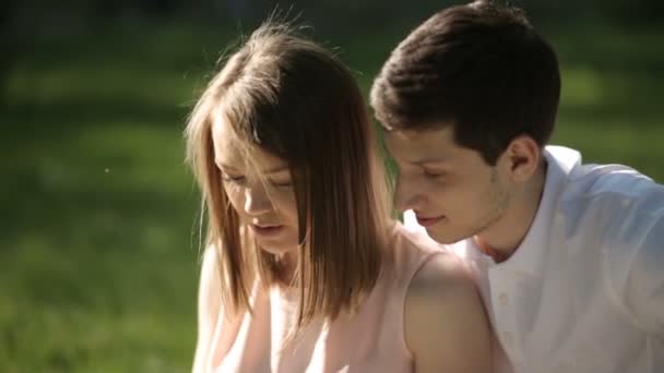 El tipo con la chica sentada en el parque y mirando la tableta. Primer plano . — Vídeo de stock