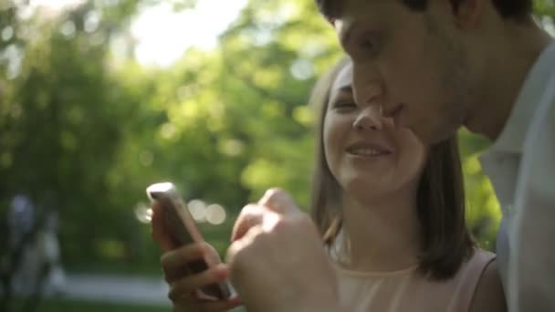 Gelukkig meisje met haar vriendje-foto's van groene boom. Close-up. — Stockvideo