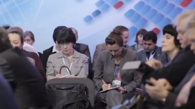 Mezhdunarodnyo konferans daki öğrenciler not defterlerinde zekice fikirler kaydederler. Yetişkin bir erkeğin elinde notlar yazmak için tablet. Kameranın düzgün hareketi.