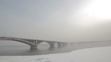 Kışın Rusya'da bir nehir üzerinde yol köprüsü. Sibirya don. Nehir buzla kaplıydı. Sibirya şehrinde çok soğuk su. Zor iklim koşulları.