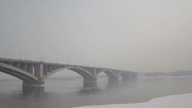 Kışın Rusya'da bir nehir üzerinde yol köprüsü. Sibirya don. Nehir buzla kaplıydı. Sibirya şehrinde çok soğuk su. Zor iklim koşulları.