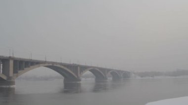 Kışın Rusya'da bir nehir üzerinde yol köprüsü. Sibirya don. Nehir buzla kaplıydı. Sibirya şehrinde çok soğuk su. Zor iklim koşulları.