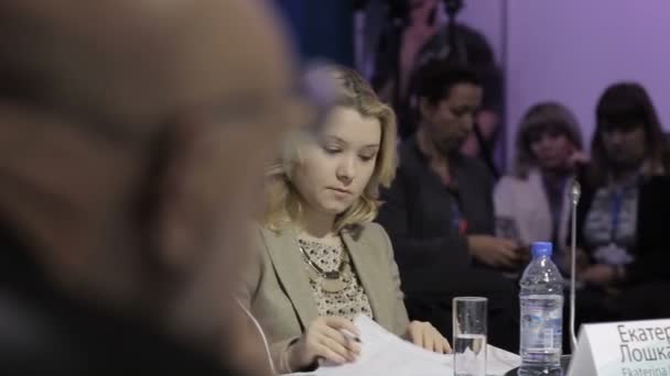 Une femme adulte écoute le rapport de l'orateur lors d'un forum économique et écrit tout dans son carnet. Salle de réunion à la table ronde. Conférence de presse . — Video