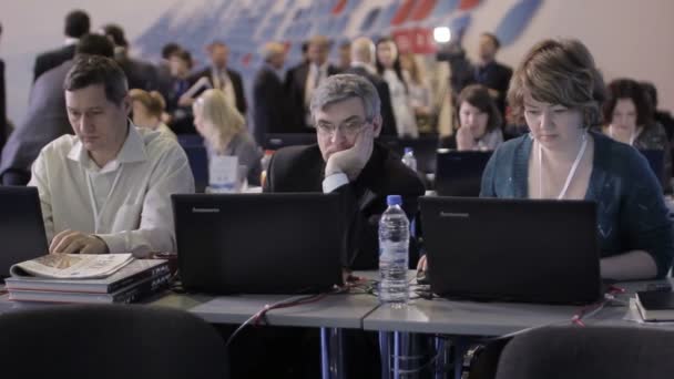 Jornalistas trabalhando em seus laptops no fórum econômico internacional. Canais de notícias no evento internacional. Entrevistas em segundo plano . — Vídeo de Stock