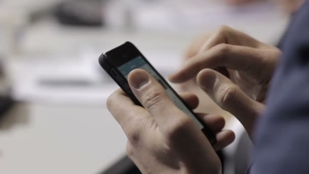 En las manos de un hombre con un teléfono móvil de pantalla táctil. Empresario sentado en una mesa redonda en un foro internacional. Él escribe un gadget tesis importantes . — Vídeo de stock