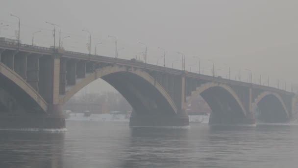 Silniční most přes řeku v zimě v Rusku. Sibiřský mráz. Řeka pokrytá ledem. Velmi studená voda ve sibiřském městě. Obtížných klimatických podmínek. — Stock video