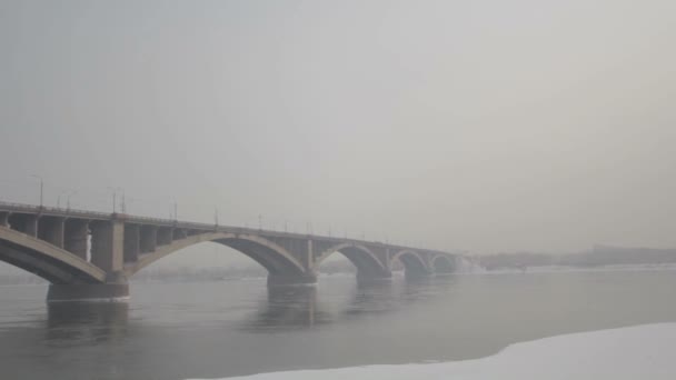 Most drogowy nad rzeką w zimie Rosji. Mróz syberyjski. Rzeka pokryta lodem. Bardzo zimna woda w syberyjskim mieście. Trudne warunki klimatyczne. — Wideo stockowe