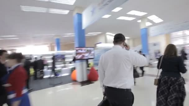 L'uomo d'affari in camicia bianca va in fondo al corridoio al forum internazionale. La telecamera si trova sul sistema di stabilizzazione. Luogo di comunicazione tra le persone . — Video Stock