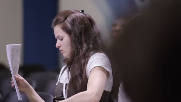 Молода дівчина на міжнародному форумі записує документи у свій файл. Ділова жінка слухає промовця звіту.. — стокове відео