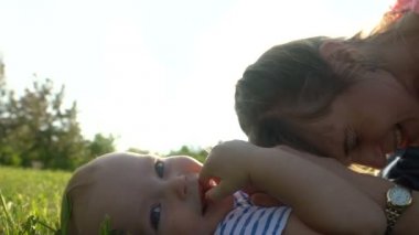 Yalan ve bir parkta yeşil bir Çimenlikte oturan bir çocuk ile genç mutlu anne