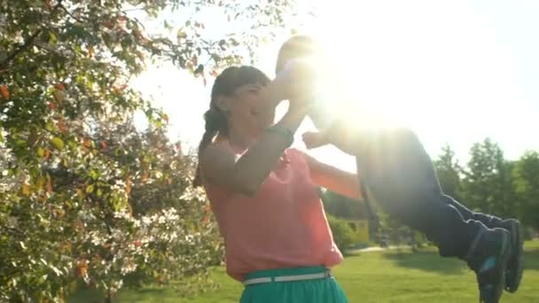 Молодая счастливая мать превращает своего любимого ребенка в своих руках — стоковое видео