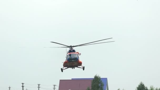 Rusland, Novosibirsk, juli 31, 2016: oranje helikopter Mi-8 over het groene veld en bomen. — Stockvideo
