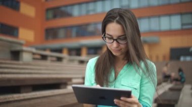 Açık alanda oturan bir dijital tablet ile güzel öğrenci.