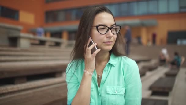 女の子はあなたの耳に携帯電話をもたらします。電話を使って魅力的な女の子. — ストック動画