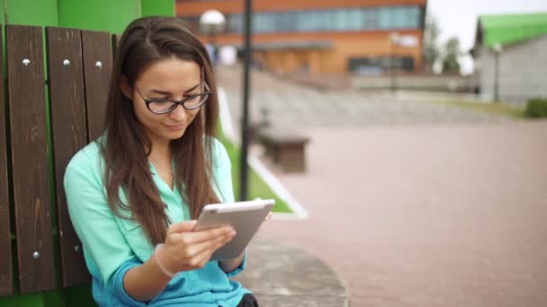 Elegantes junges Mädchen mit dem Mini-Tablet. schöne Studentin mit Brille — Stockvideo