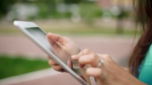 Manos de mujer con el mini comprimido blanco. Mujer incierta utiliza una pantalla táctil — Vídeos de Stock