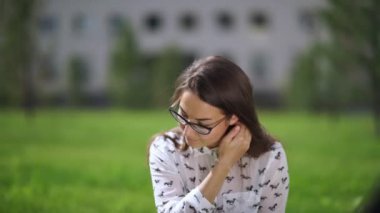 Çimenlerin üzerinde oturan dijital tablet ile gözlük güzel öğrenci