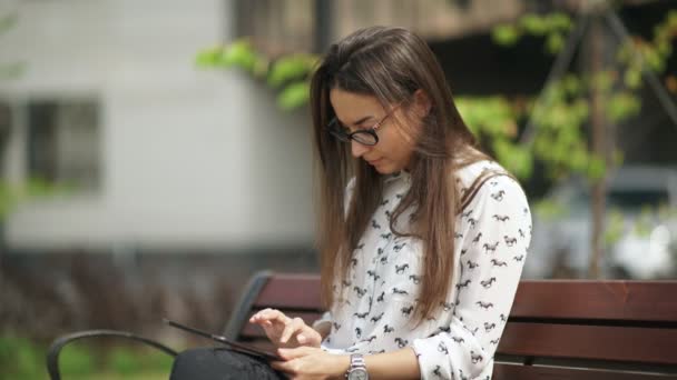 Krásná studentka v brýlích s digitálním tabletu posezení venkovní — Stock video