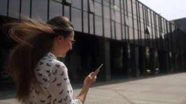 Güzel kız sokakta wakling ve bir akıllı telefon kullanarak