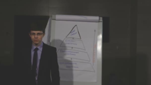 Confident young businessman talking straight. Flip-chart behind — Stock Video