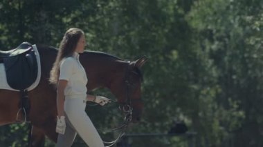 Beyaz elbiseli binici atı dizginleri tarafından yol açar. Kadın binici