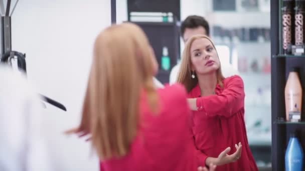 Vrouw met een nieuw kapsel in een schoonheidssalon in de spiegel kijken — Stockvideo