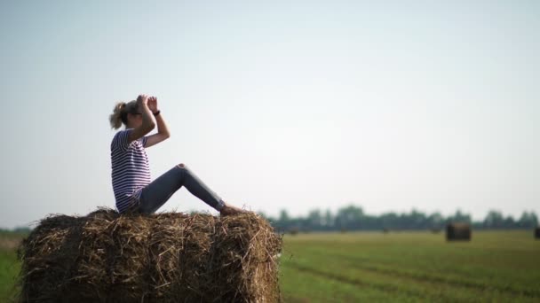 Lány a vidéken. Csinos lány ül a Szénaboglyák — Stock videók