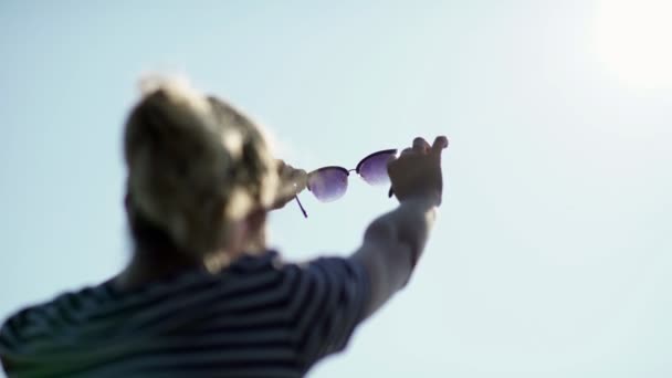 Flicka i solglasögon tittar in i fjärran. Flicka på landsbygden. — Stockvideo