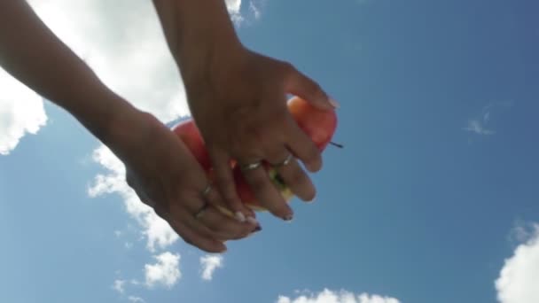 La mano femenina vomita manzanas sobre un fondo de cielo azul. Lento. — Vídeo de stock