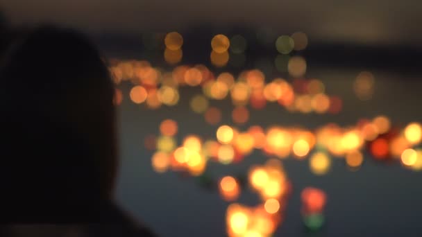 Silhouette di una ragazza sul lungomare. La ragazza guarda le lanterne dell'acqua — Video Stock