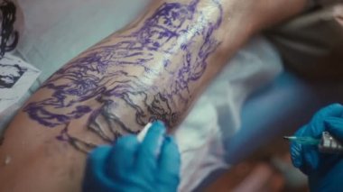 tıbbi steril eldiven aster dövme müşteri bacak üzerinde bir dövme desenleme