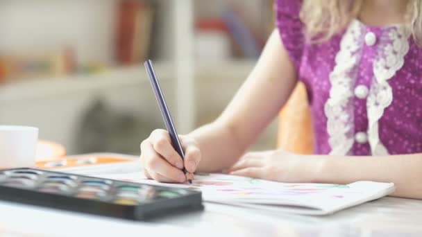 Kleines Mädchen zeichnet einen blauen Bleistift. Mädchen sitzt am Schreibtisch und zeichnet. — Stockvideo