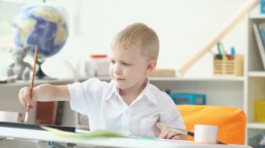 İlkokul çağında sevimli çocuk suluboya boyar. Erkek 5-7 yaş