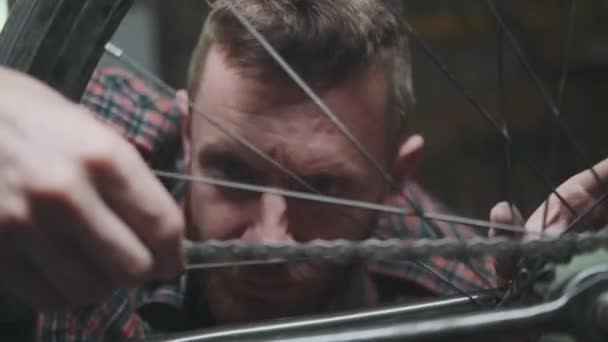 Hombre reparando una bicicleta en taller atmosférico — Vídeo de stock