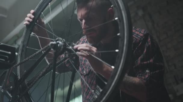 Ремонт велосипедного колеса: человек с бородой занят в мастерской. — стоковое видео