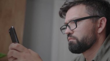 Gözlüklü ve sakallı bir ofis çalışanı mesaj yazıyor.