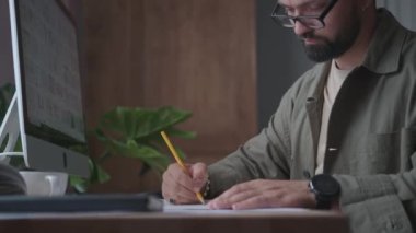 Bir adam ofisinde bir proje üzerinde çalışır, yazar ve çizer.