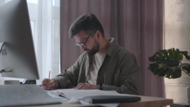 Bir adam merkez büroda çalışıyor ve belgeler çiziyor.