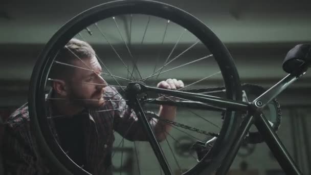O ciclista repara a moto em uma garagem, vira a roda — Vídeo de Stock