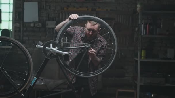 De man kijkt naar het spinnewiel. Fietsreparatie, klein bedrijf. — Stockvideo