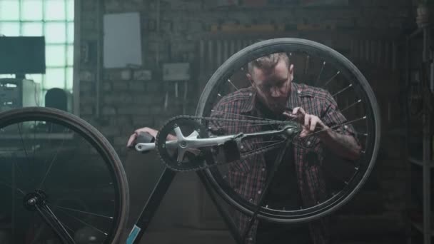 Atmosfer atölyesi, garaj: hippi bir adam bisikleti tamir ediyor — Stok video