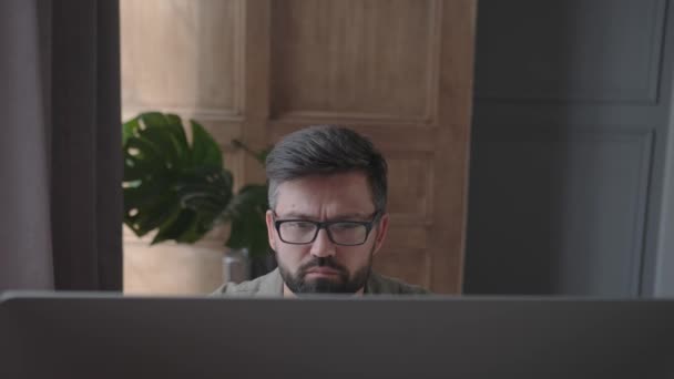 Expresión facial de un hombre en proceso de trabajar en el ordenador — Vídeos de Stock